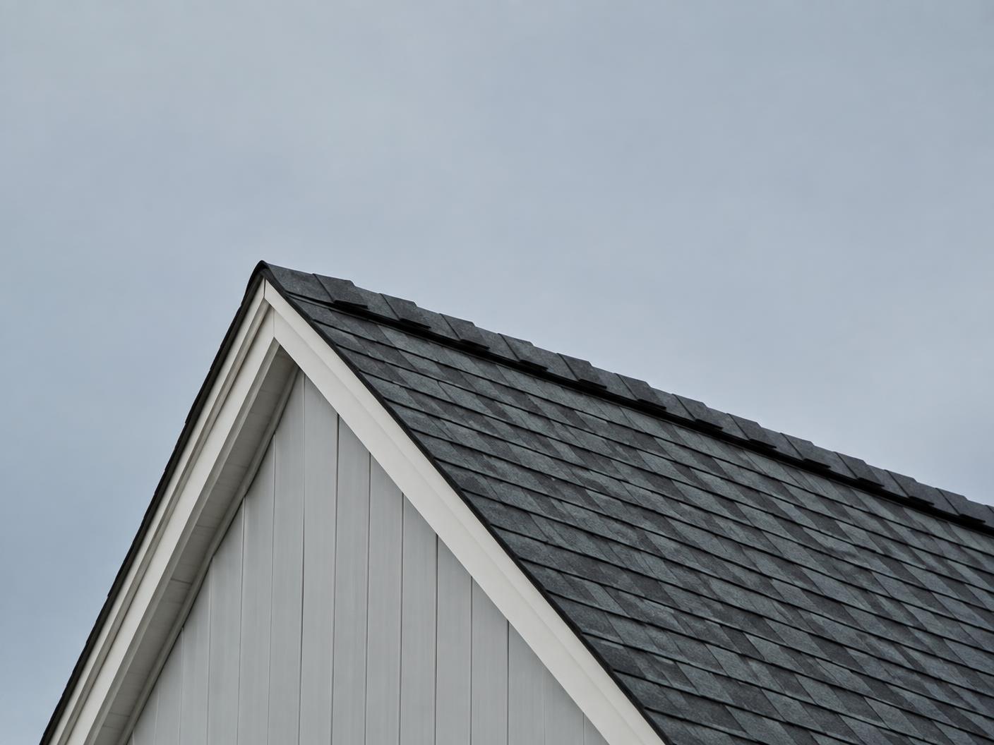Steep shingled roofline and gable edge against a soft grey Canadian sky