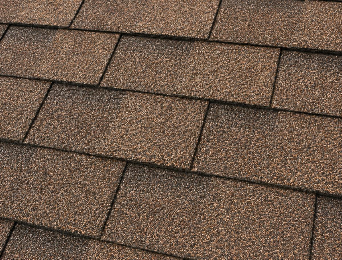 Close-up of brown three-tab asphalt roofing shingles in even rows